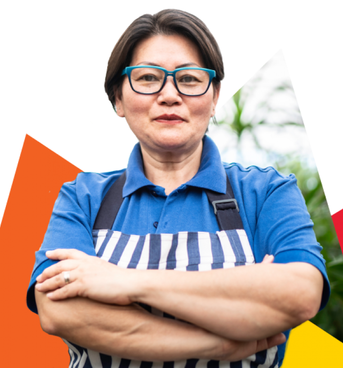 Woman with arms crossed against a background with red, orange and yellow triangular shapes